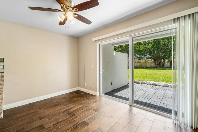 an empty room with floor to ceiling windows and ceiling fan