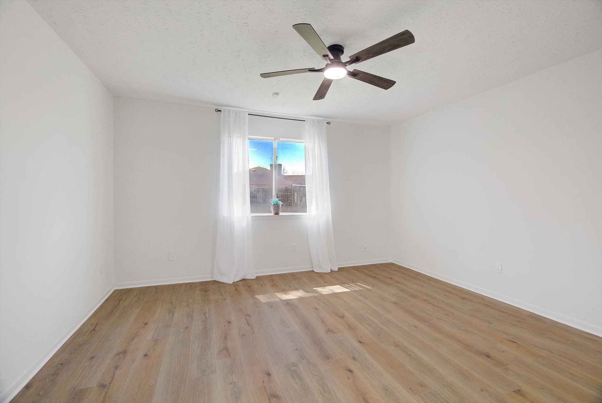 15110 Peachmeadow Lane Channelview, TX 77530 - Photo 19 of 34 an empty room with wooden floor chandelier fan and windows