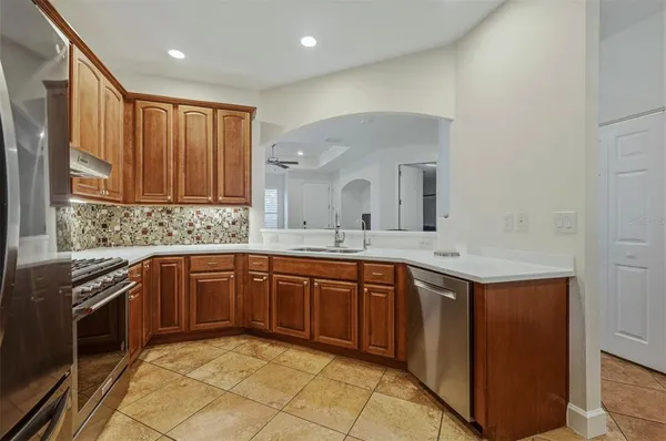 a kitchen with stainless steel appliances granite countertop a refrigerator a stove and a sink with wooden cabinets