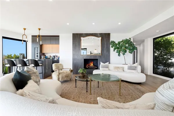 a living room with furniture large windows and wooden floor
