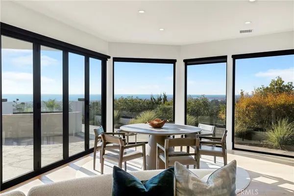 a dining room with wooden floor a chandelier a glass table and chairs