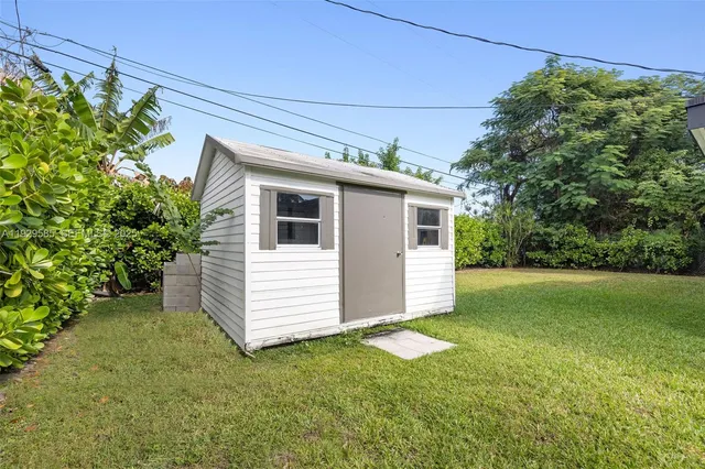 a view of a white house next to a yard with potted plants