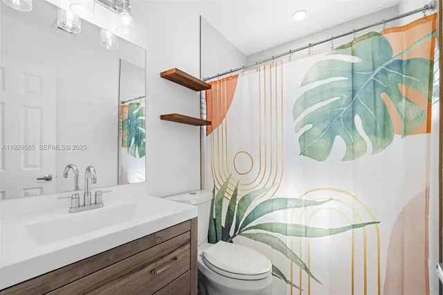 a bathroom with a sink a mirror a toilet and shower