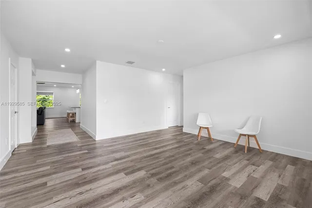 a view of a livingroom with wooden floor and a kitchen