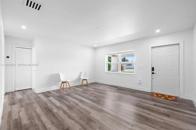 a view of empty room with wooden floor and window