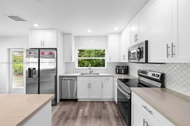 a kitchen with stainless steel appliances granite countertop a refrigerator sink and stove