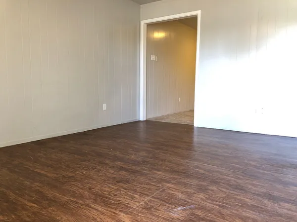 a view of an empty room with wooden floor and closet