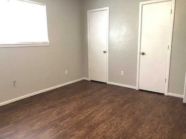 an empty room with wooden floor and window