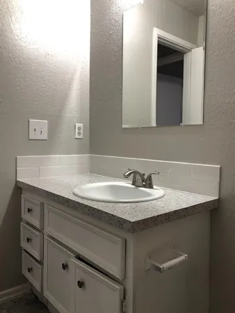 a bathroom with a granite countertop sink and white cabinets