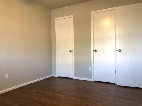 a view of an empty room with wooden floor and closet