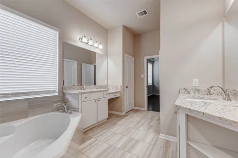 a spacious bathroom with a granite countertop double vanity sink a mirror and a shower