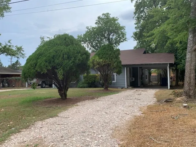 a view of a house with a yard and large tree