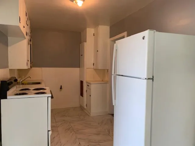 a white refrigerator freezer and a stove sitting inside of a kitchen