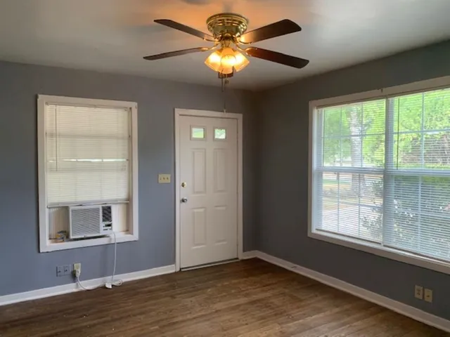 a view of an empty room with window and wooden floor