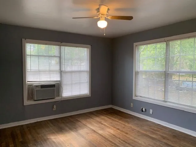 a view of an empty room with a window and wooden floor