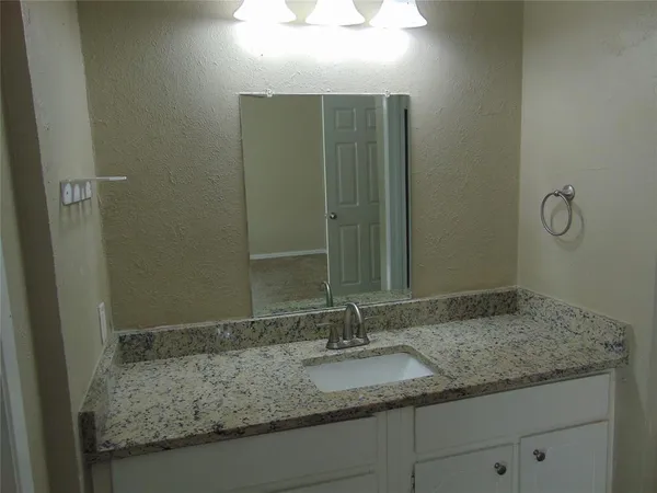 a bathroom with a granite countertop sink and a mirror