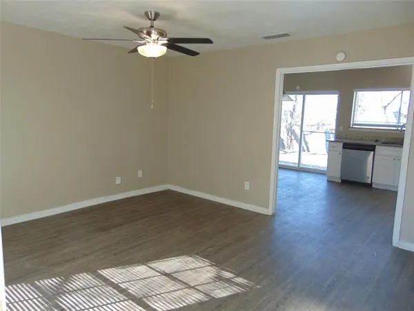 a view of an empty room with a window and wooden floor