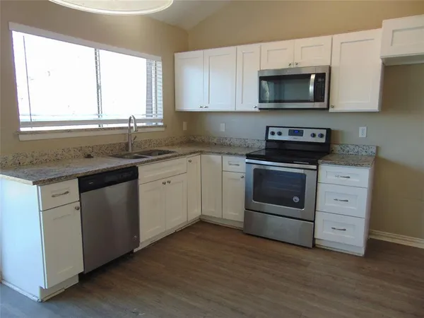 a kitchen with stainless steel appliances granite countertop a stove a sink and a microwave