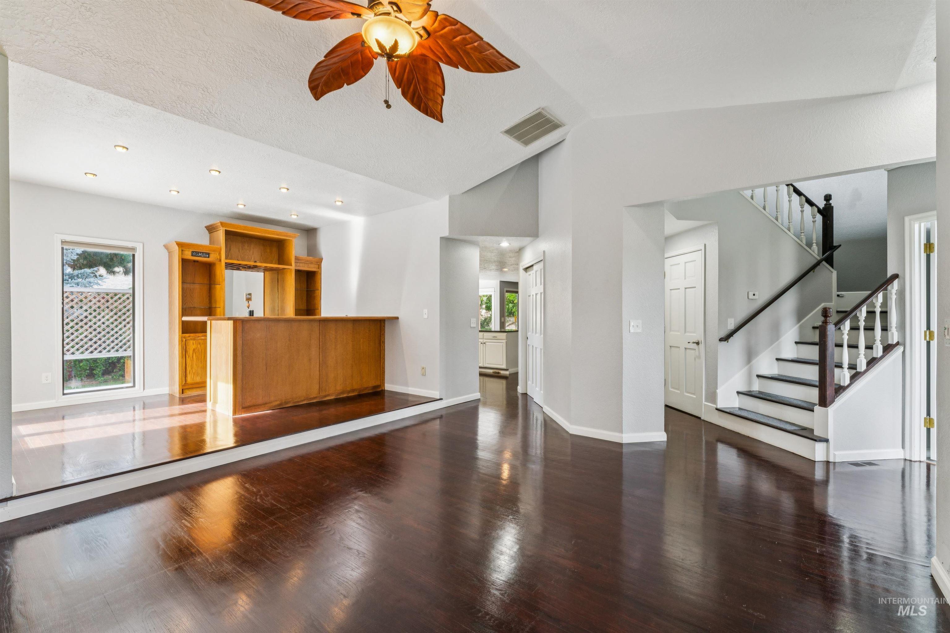 9831 West Ripley Street Boise, ID 83704 - Photo 6 of 47 Spacious living area featuring rich wood-finish flooring, a decorative ceiling fan, and multiple windows with wood blinds