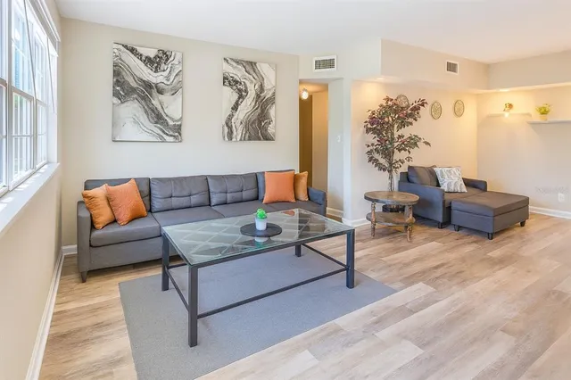a living room with furniture and a potted plant on a dresser