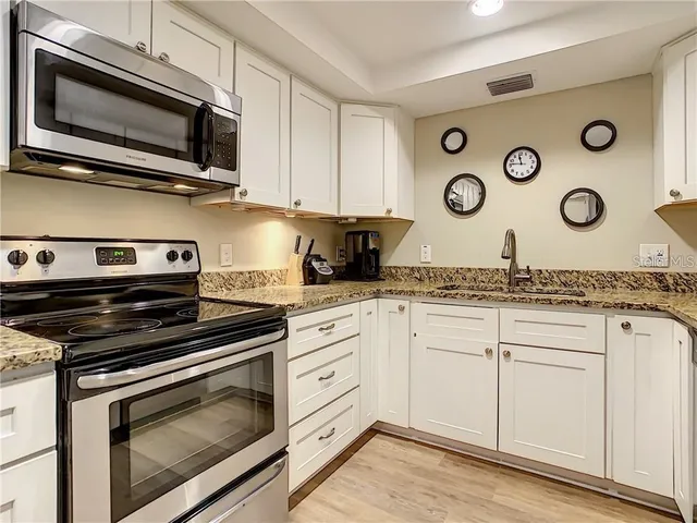 a kitchen with granite countertop cabinets stainless steel appliances and a wooden floor