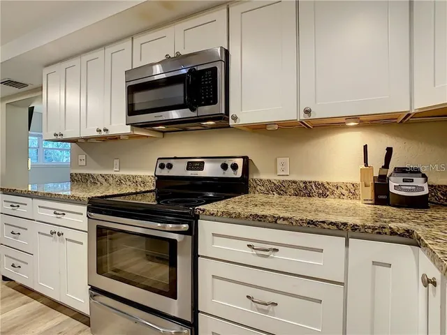 a kitchen with stainless steel appliances granite countertop white cabinets stove a sink and dishwasher