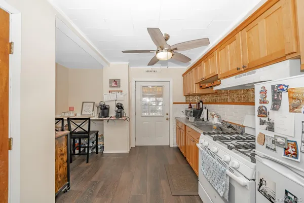 a kitchen with stainless steel appliances granite countertop a stove top oven a sink a dining table and chairs with wooden floor