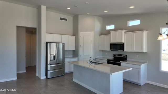 a kitchen with stainless steel appliances a refrigerator a stove a sink and white cabinets