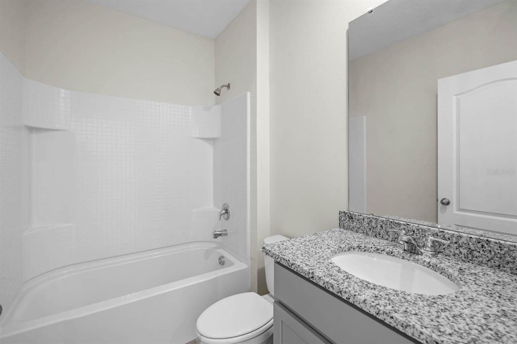 1217 Alstonia Mount Mount Dora, FL 32757 - Photo 13 of 33 a bathroom with a granite countertop sink toilet mirror and bathtub