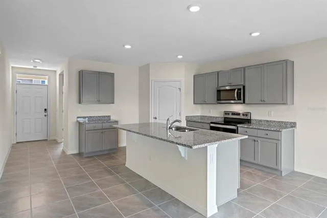 a kitchen with stainless steel appliances a sink a stove a microwave a sink a counter top space cabinets and a window