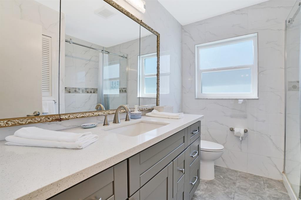 4101 Northeast 24th Avenue Lighthouse Point, FL 33064 - Photo 17 of 30 a bathroom with a granite countertop sink a toilet and a mirror