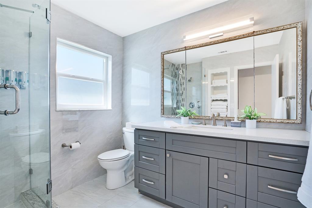 4101 Northeast 24th Avenue Lighthouse Point, FL 33064 - Photo 25 of 30 a bathroom with a granite countertop sink a toilet and a mirror