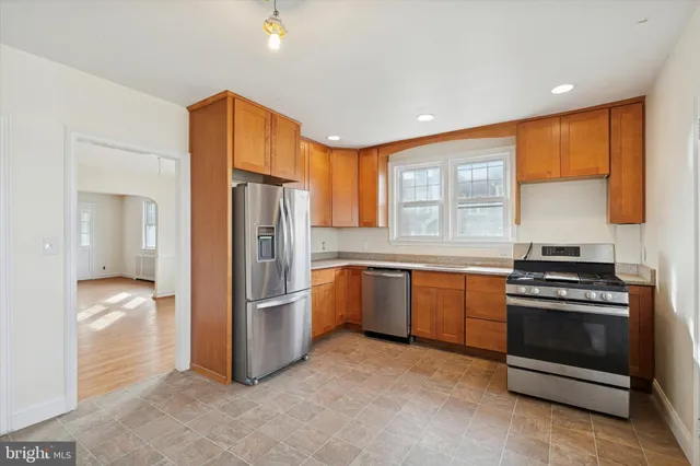 a kitchen with stainless steel appliances granite countertop a refrigerator a stove and a sink