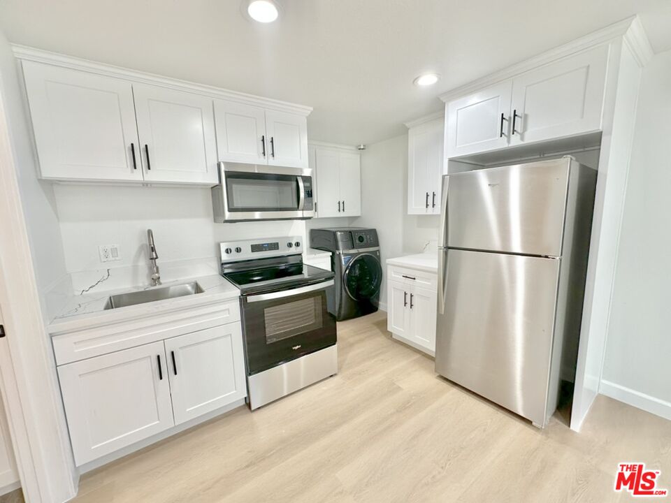 10720 Charnock Road Los Angeles, CA 90034 - Photo 30 of 33 a kitchen with cabinets stainless steel appliances and wooden floor