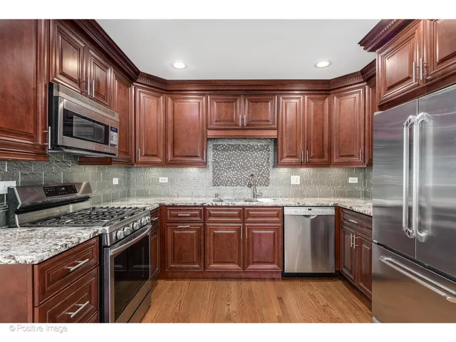 a kitchen with stainless steel appliances granite countertop a stove a sink dishwasher a refrigerator and cabinets with wooden floor