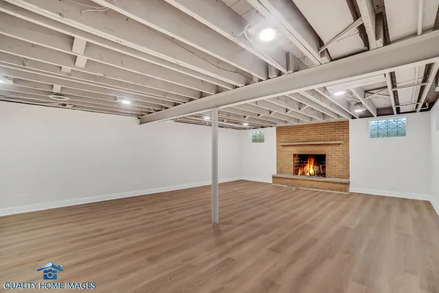 a view of an empty room with wooden floor and a fireplace