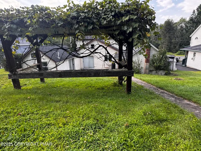 a white house with a yard and a large tree