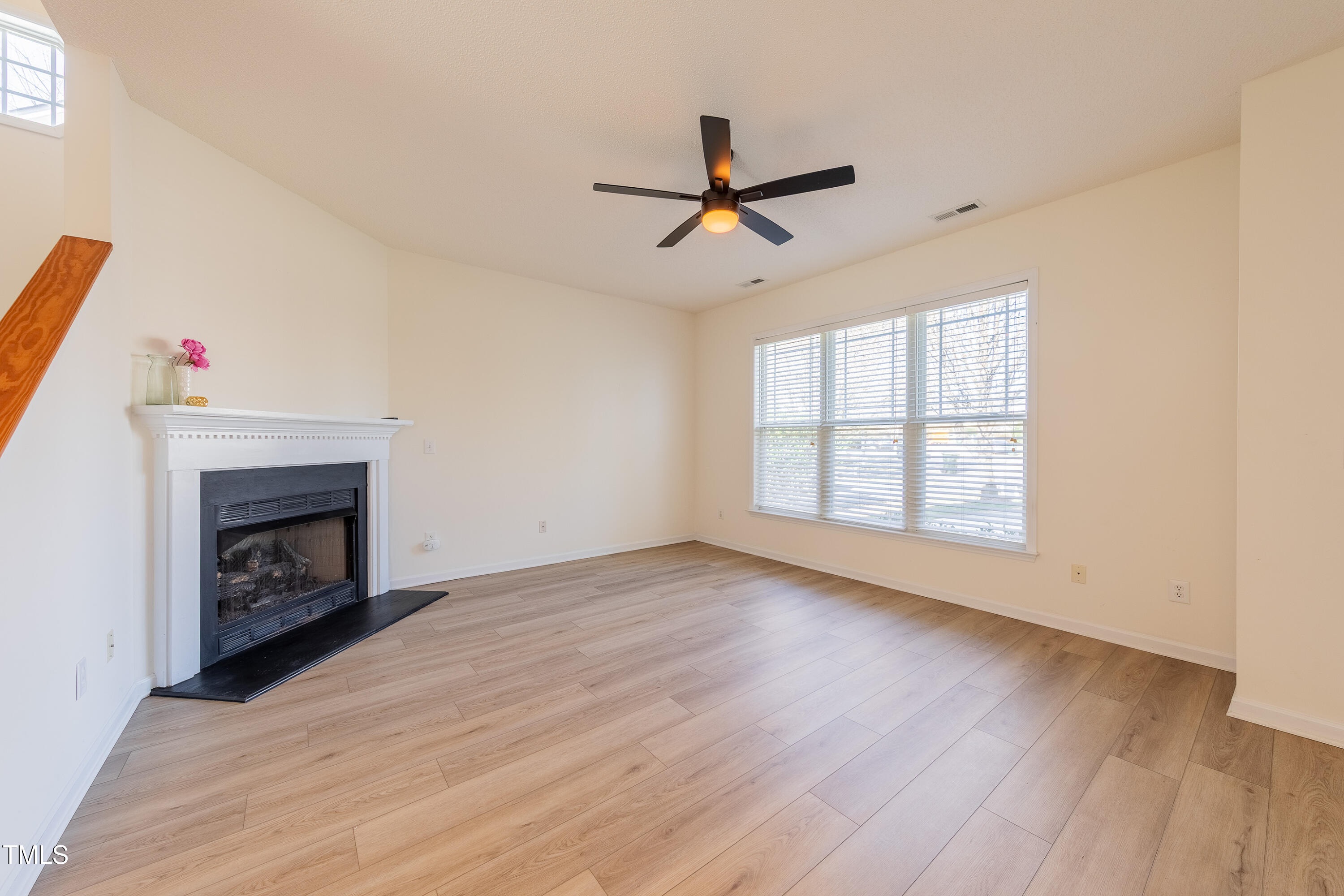 10809 Farmville Road Raleigh, NC 27614 - Photo 6 of 28 an empty room with windows a fireplace and wooden floor
