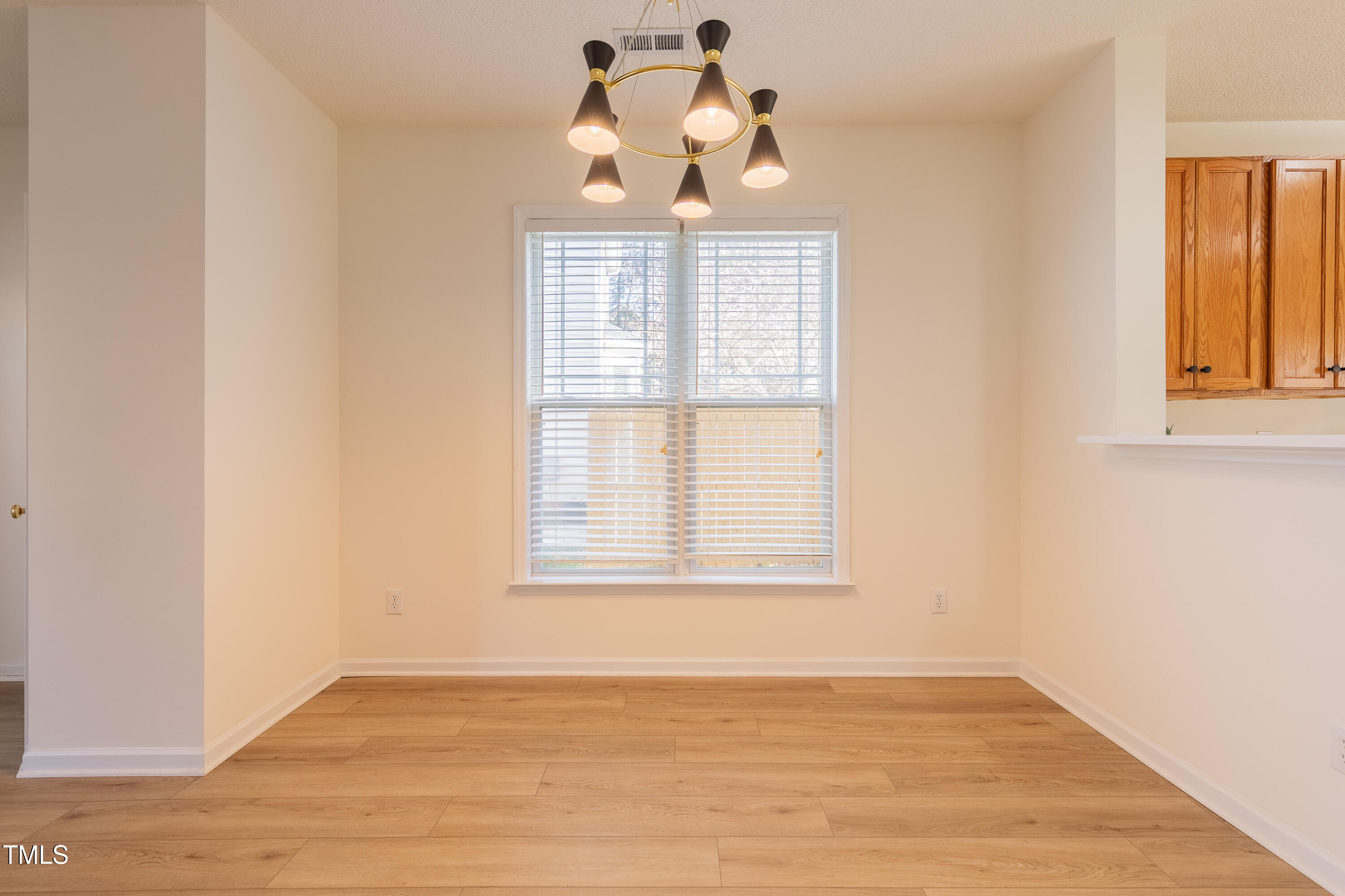 10809 Farmville Road Raleigh, NC 27614 - Photo 9 of 28 an empty room with wooden floor chandelier fan and windows