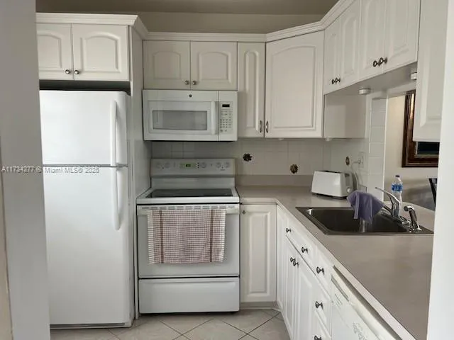 a kitchen with white cabinets and white appliances