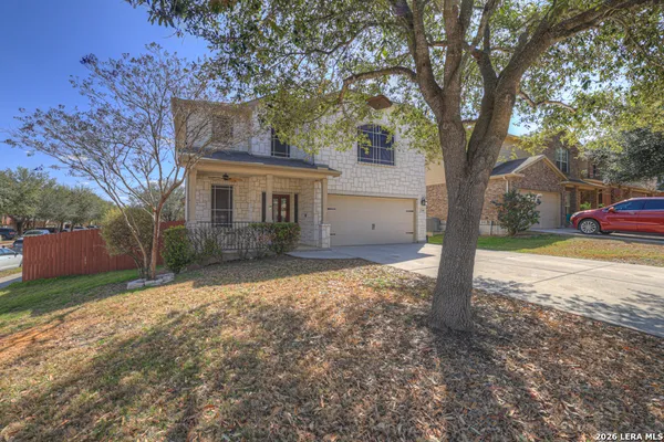 a front view of a house with a yard and large tree