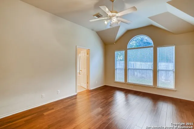 an empty room with wooden floor fan and window
