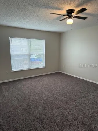 an empty room with windows and fan