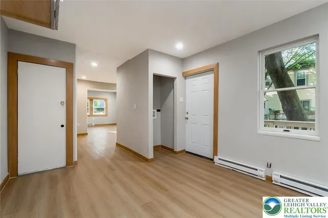 a view of an empty room with wooden floor and a window
