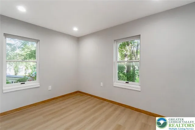 an empty room with wooden floor and windows