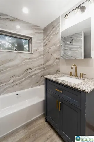 a bathroom with a granite countertop bathtub a sink and mirror