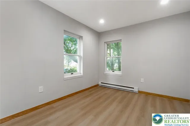 an empty room with wooden floor and windows