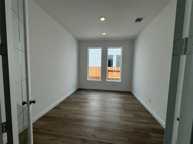 a view of an empty room with wooden floor and a window