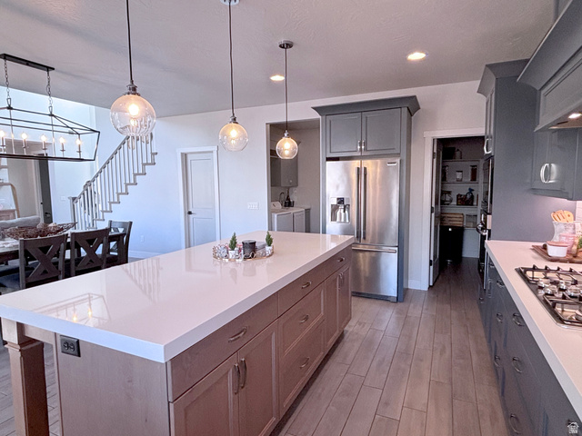 429 East Treasure Road Washington, UT 84780 - Photo 15 of 36 Kitchen with stainless steel appliances, decorative light fixtures, light wood finished floors, two tone cabinetry, and a kitchen island