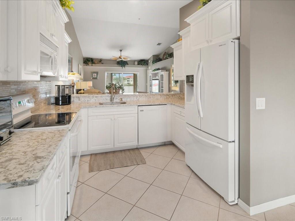 2810 Cypress Trace Circle, Unit 2127 Naples, FL 34119 - Photo 9 of 28 a kitchen with stainless steel appliances granite countertop a refrigerator sink and white cabinets